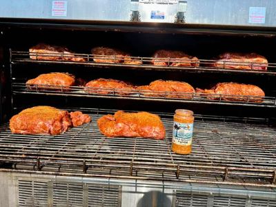 Racks of seasoned pork shoulder slow-cooking on a large barbecue smoker